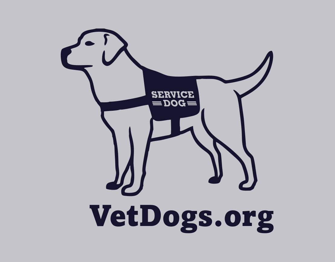 the image shows an up close shot of the service dog cartoon in a vest that is located on the back neck of the shirt. Below the image is the text, "VetDogs.org" the image and text is in navy blue 