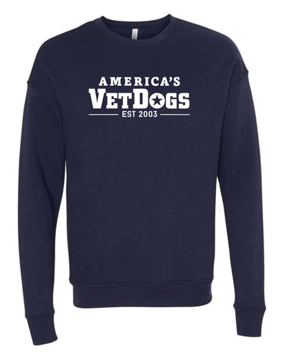 Front facing photo of a long sleeved crew neck sweatshirt in navy blue shirt. The shirt as a fitted bottom. The shirt has fitted wrists. The front of the shirt says "America's VetDogs EST. 2003"  in white colored letters